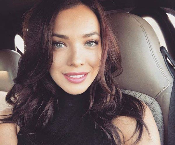 Woman in White Long Sleeve Shirt Standing Beside Window